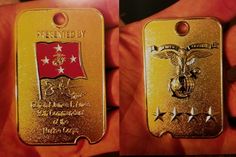 two gold tags that have been placed in someone's hand, one has a red and white flag on it