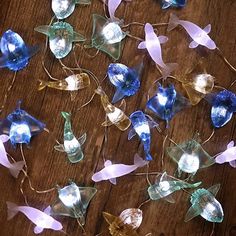 several small glass flowers on a wooden table with string lights attached to the stems and petals