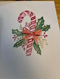 a christmas card with candy canes and holly leaves on the front, painted in watercolor