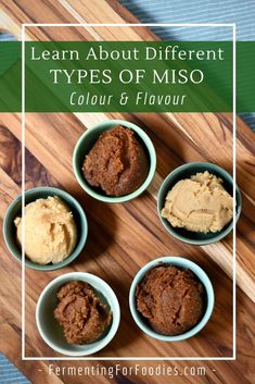 four bowls filled with different types of miso on top of a wooden cutting board