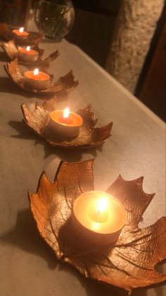 four candles are lit on leaf shaped plates