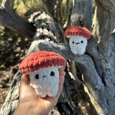 a hand holding a small stuffed animal in front of a tree with two faces on it