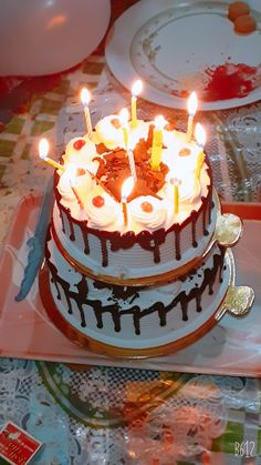 a birthday cake with lit candles sitting on a table