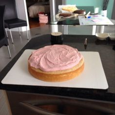 a cake with pink frosting sitting on top of a counter