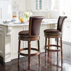 two brown leather stools sitting in front of a kitchen island