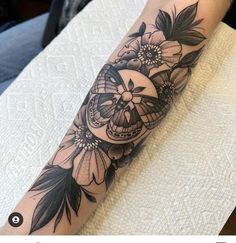 a person with a tattoo on their arm that has flowers and a skull in it