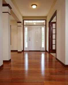 an empty hallway with wooden floors and white walls