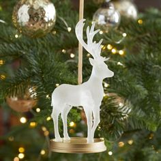 a glass ornament with a deer on it in front of a christmas tree