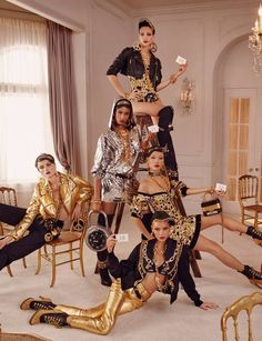 a group of people dressed in gold and black posing for a photo with chandeliers