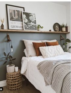 a bed sitting in a bedroom next to a wooden shelf filled with plants and pictures