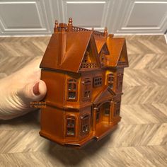 a hand is holding a toy house on the floor