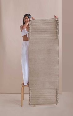 a woman is holding up a large rug with fringes on the bottom and sides