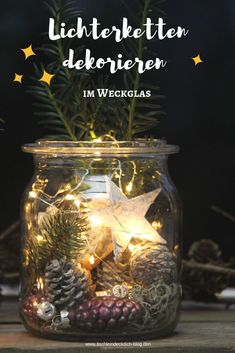 a glass jar filled with christmas lights and pine cones on top of a wooden table