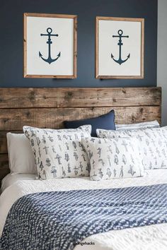 two framed pictures above a bed in a bedroom with blue walls and white linens