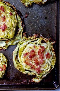 four artichokes on a baking sheet with bacon and cheese in the middle