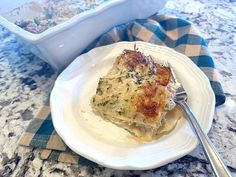 a white plate topped with lasagna next to a casserole dish