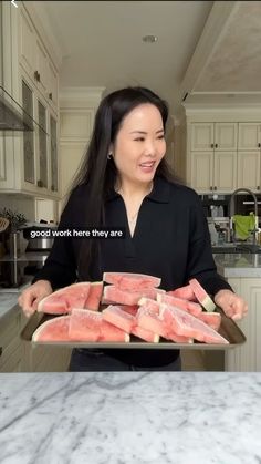 a woman holding a tray full of watermelon slices