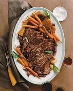 a white plate topped with meat and veggies next to a glass of wine