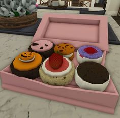 an open pink box filled with lots of different types of donuts on top of a table