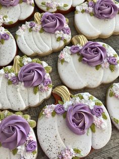 decorated cookies with purple frosting and flowers on wooden table next to white pumpkins