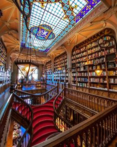 an ornate library filled with lots of books and stained glass ceiling lights above the stairs