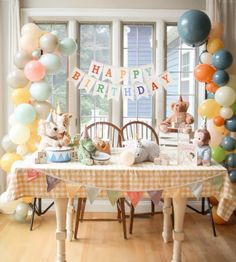 a birthday party is set up with balloons and stuffed animals on the table in front of it