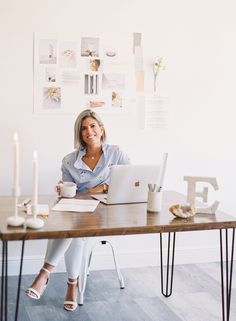 a woman sitting at a table with a laptop and coffee in front of her, surrounded by candles