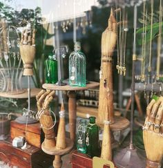 several wooden objects are displayed in a shop window with green glass bottles and other items