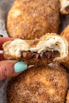 a person holding a doughnut in their left hand with chocolate filling on the inside