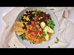 a white plate topped with rice, beans and avocado next to tortilla chips