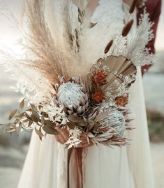 a bride and groom standing next to each other in front of the ocean holding their bouquet