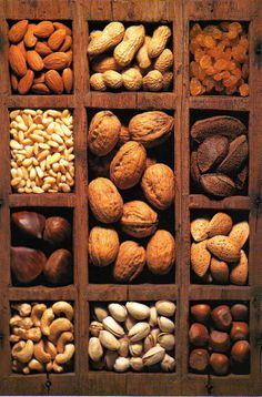 an assortment of nuts in wooden boxes on top of each other, including almonds and peanuts