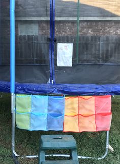 a blue trampoline with several different colored squares on it's sides and a green step stool in front of it