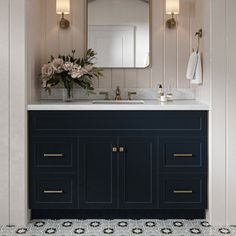 a white and blue bathroom with flowers on the counter top, two mirrors above the sink