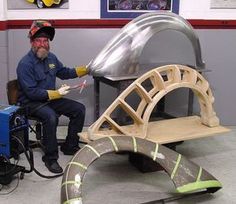 a man sitting on a bench made out of plywood and metal parts in a garage