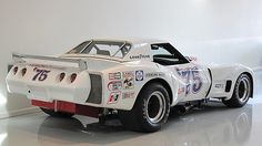 a white race car with numbers painted on it's side, parked in a garage