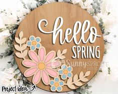 a wooden sign that says hello spring with flowers and leaves on the bottom, in front of some white flowers