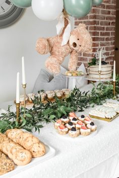 a table topped with cookies and desserts next to a teddy bear hanging from the ceiling