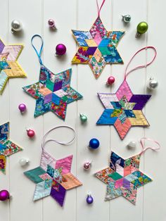 christmas ornaments are laid out on a white surface with colorful stars hanging from the ceiling