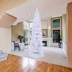 a white christmas tree sitting in the middle of a living room next to a fireplace