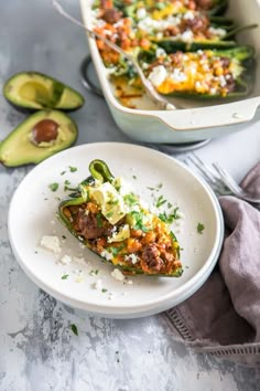 an enchilada is on a plate next to avocado and another dish