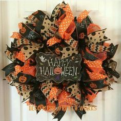 a halloween wreath on the front door with an orange and black polka dot bow hanging from it