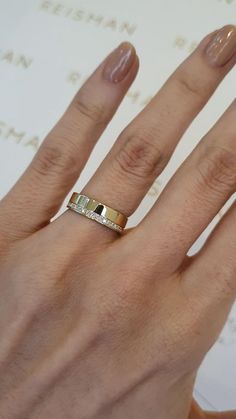 a woman's hand with a gold ring on top of her finger and two diamonds in the middle