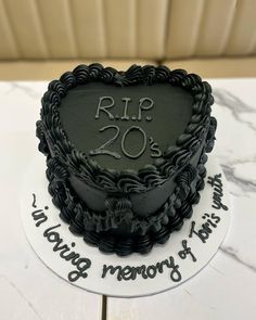 a black and white cake sitting on top of a table next to a sign that says rip 20 years