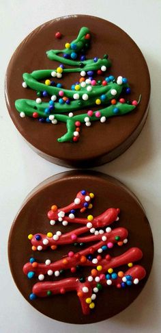 two chocolate decorated cookies with sprinkles and christmas trees on them are sitting side by side