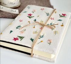 a white book with flowers on it next to a roll of twine