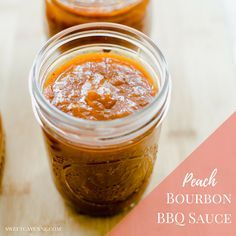 two jars of peach bourbon bbq sauce sitting on a wooden table with the words peach bourbon bbq sauce