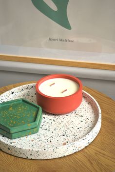 a candle sits on a tray next to a container