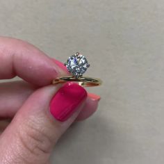 a woman's hand holding an engagement ring with a diamond on the top and bottom