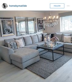 a living room filled with lots of furniture next to a chandelier hanging from the ceiling